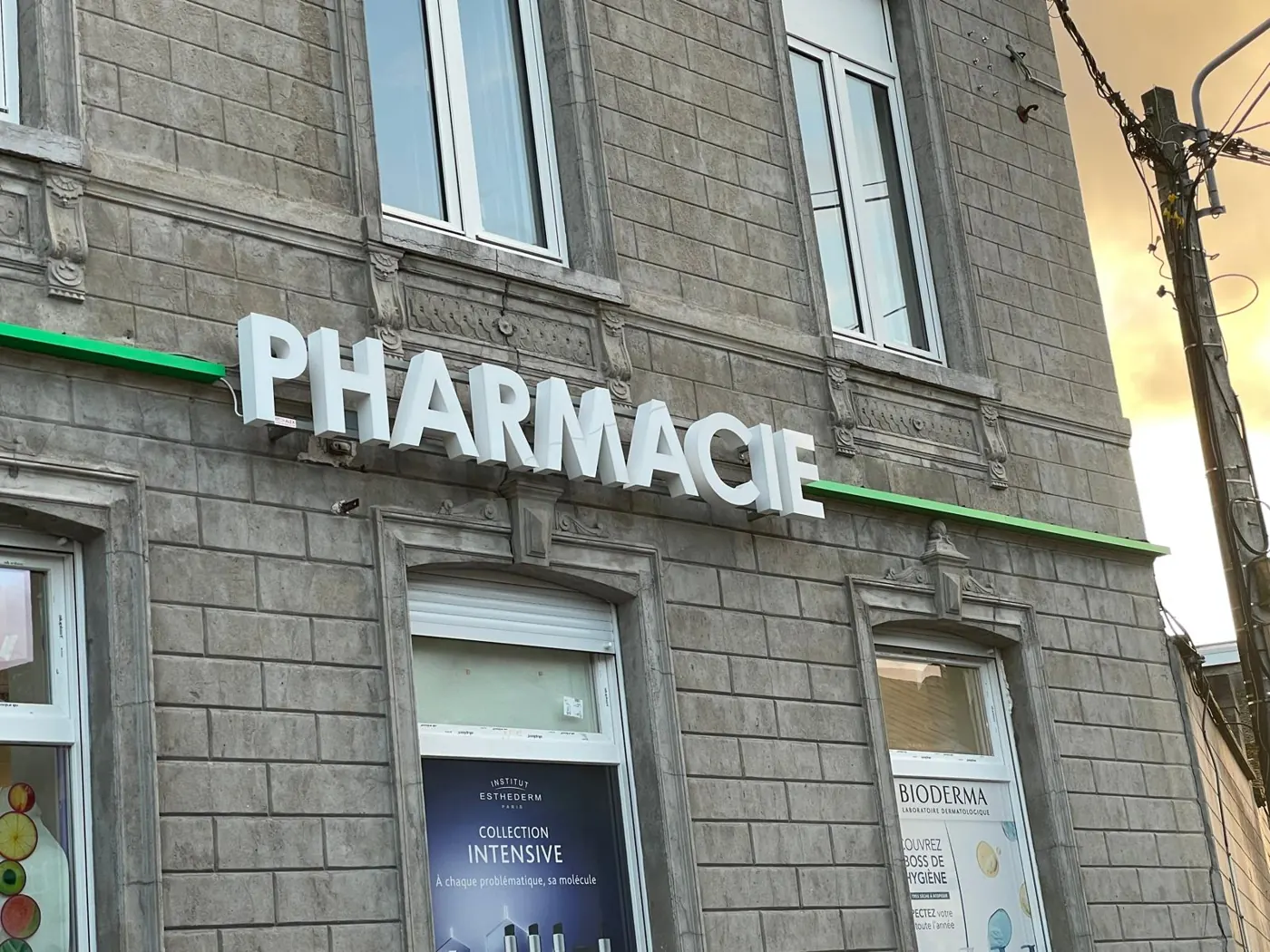 Devanture de pharmacie rénovée avec enseigne en lettres blanches et bandeau vert